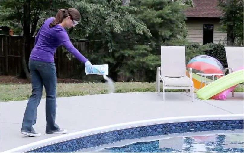 woman adding shock to pool